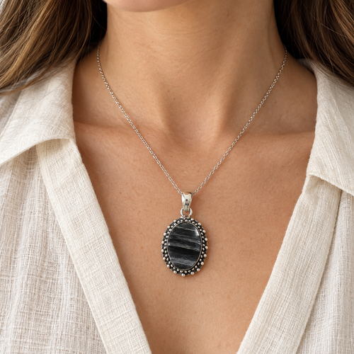 Close view of a medium black tourmaline pendant worn on a silver-tone chain.