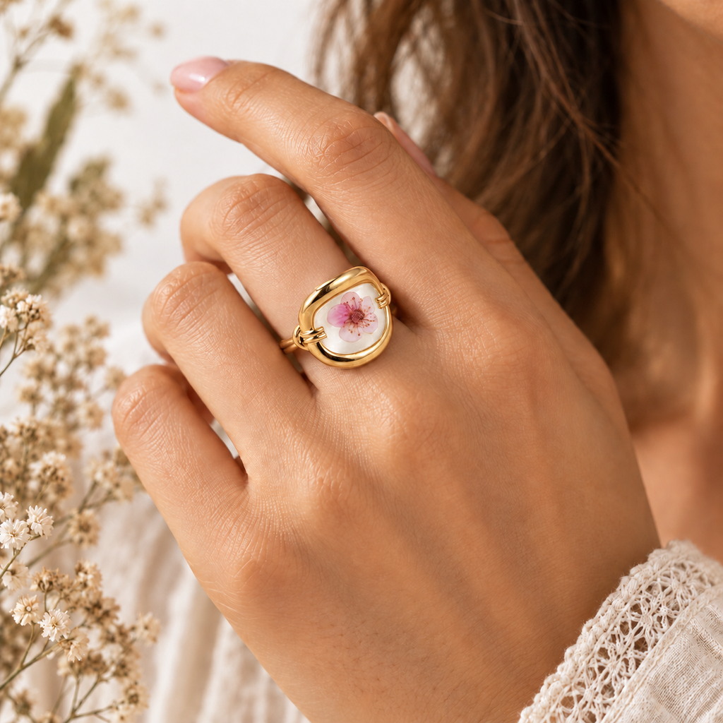 Model hand wearing the Radiant Renewal Ring with a single reddish pressed blossom