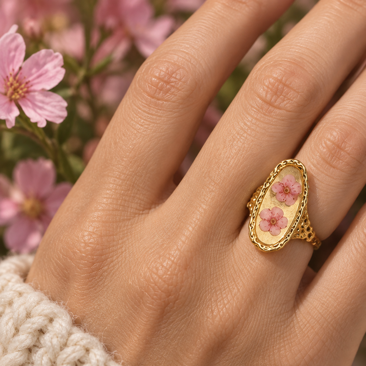 Model hand wearing the Blush Blossom Becoming Ring with two soft blush pressed blossoms