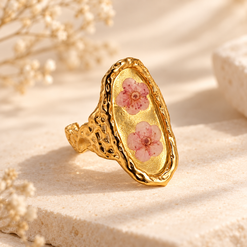 Blushing Blossom Renewal Ring with two pink pressed blossoms in a gold-tone setting on a warm botanical background