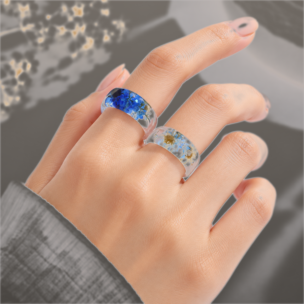 Model wearing Cobalt Cluster and Skyglass Bloom Faceted Wildflower Resin Rings on hand