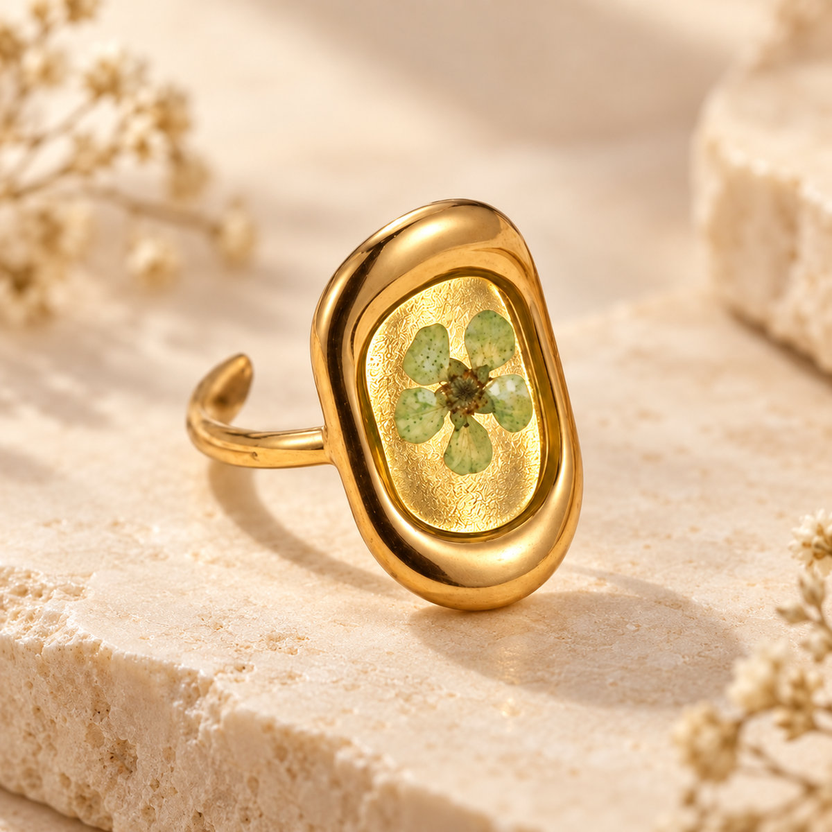 Meadow Green Bloom Ring with a pale green pressed flower in a smooth gold-tone oval setting on a warm botanical background