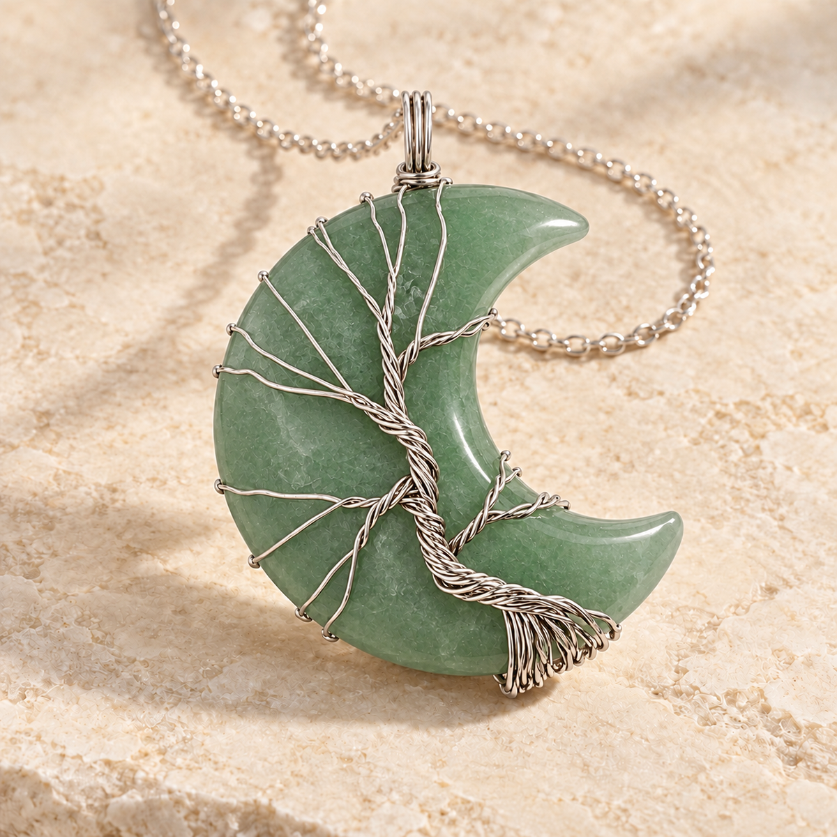 Green Aventurine crescent moon necklace wrapped with a silver-tone Tree of Life on a warm cream background.