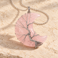 Rose Quartz crescent moon necklace wrapped with a silver-tone Tree of Life on a warm cream background.