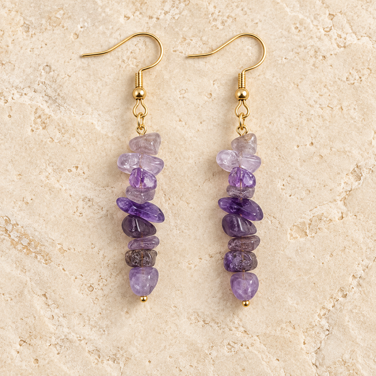 Amethyst stone chip drop earrings with gold-tone hooks on a warm cream background.