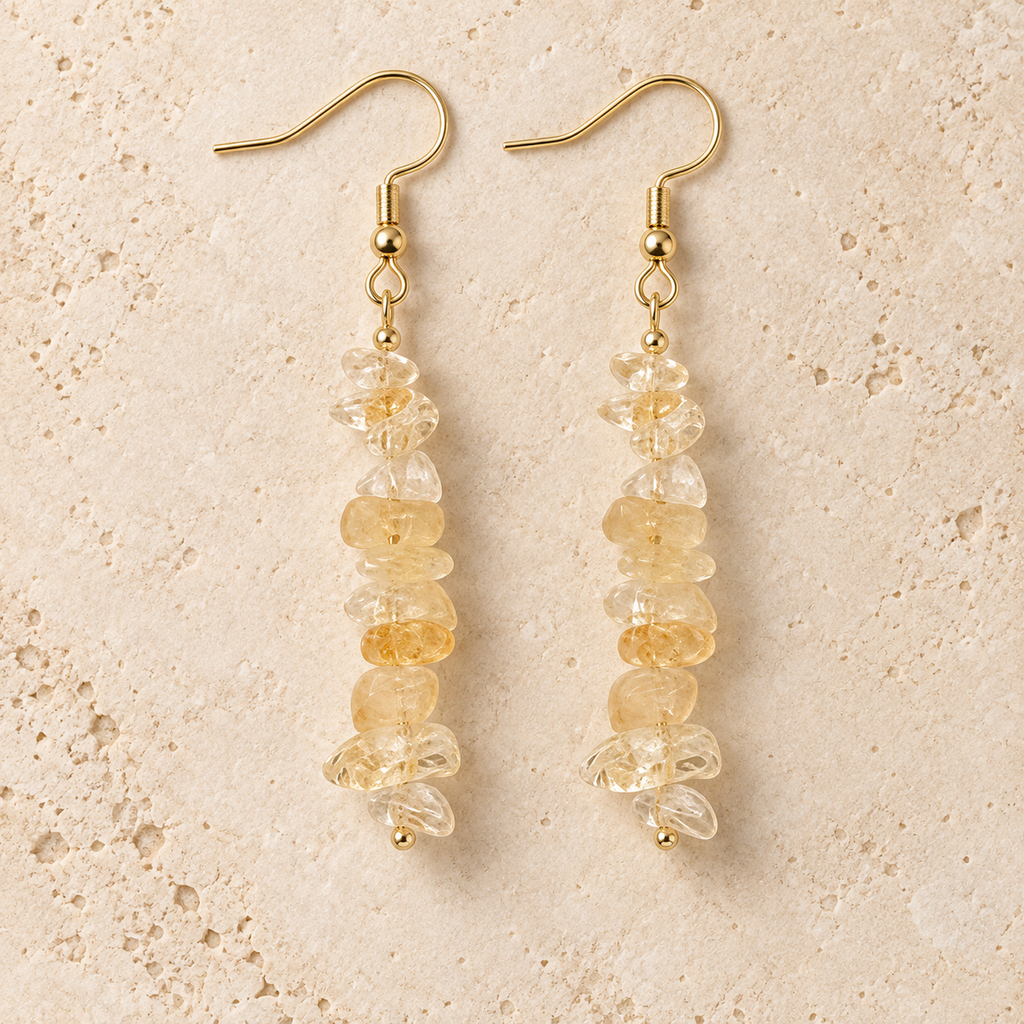Citrine stone chip drop earrings with gold-tone hooks on a warm cream background.