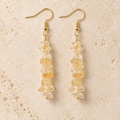 Citrine stone chip drop earrings with gold-tone hooks on a warm cream background.