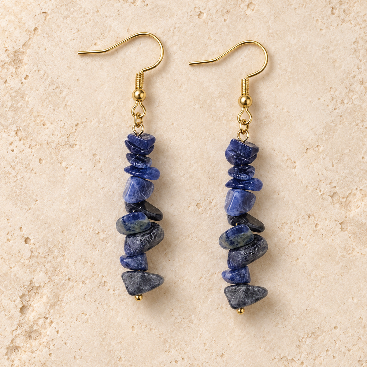 Sodalite stone chip drop earrings with gold-tone hooks on a warm cream background.