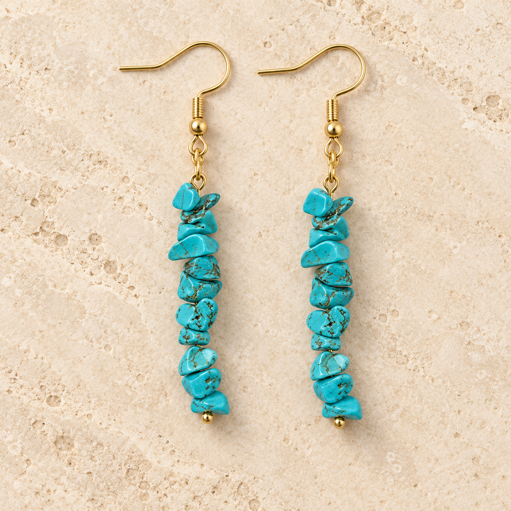 Turquoise stone chip drop earrings with gold-tone hooks on a warm cream background.