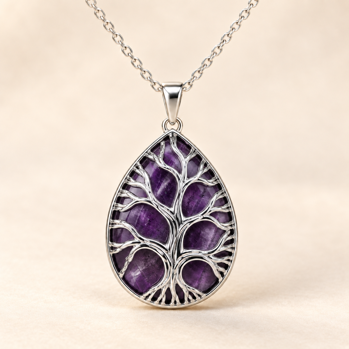 Dark Amethyst teardrop Tree of Life necklace on a warm cream background.