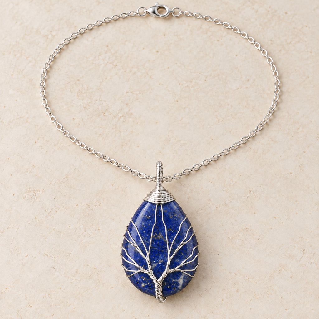 Lapis Lazuli teardrop Tree of Life necklace on a warm cream background.
