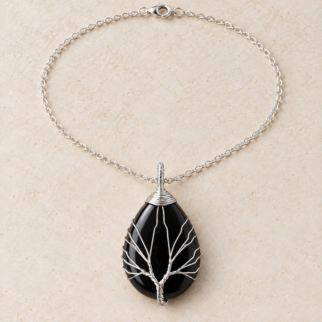 Obsidian teardrop Tree of Life necklace on a warm cream background.