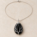 Obsidian teardrop Tree of Life necklace on a warm cream background.