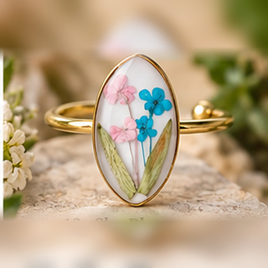 Sky Blossoms adjustable stainless steel pressed-flower ring with pink and blue blossoms on a pale background.